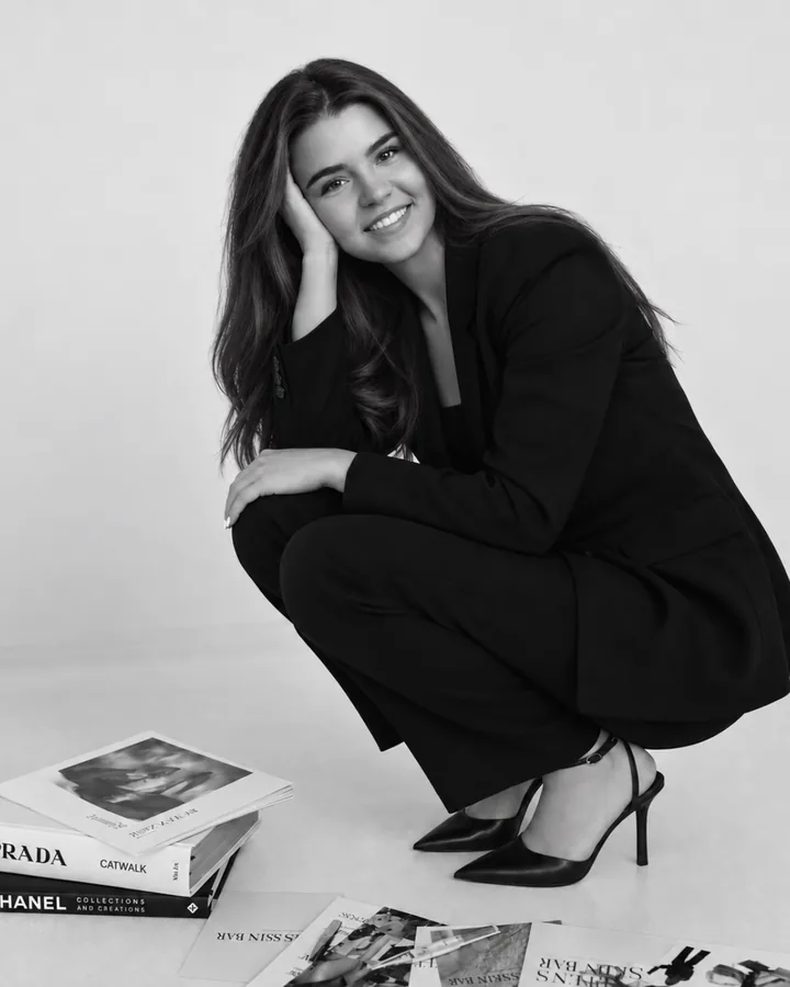 Celine, Gründerin und CEO von SocialMediaGRP, im Agentur‑Shooting — in Schwarz, umgeben von Modemagazinen